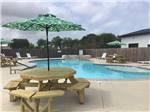 A table with an umbrella next to the swimming pool at PORT O'CONNOR RV PARK - thumbnail