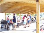 Campers line up for buffet under wooden canopy at TOPSAIL SOUND RV PARK - thumbnail