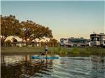 A woman and her dog paddling on a board at GULF SHORES RV RESORT - thumbnail