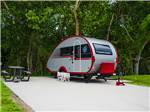 A small travel trailer in a paved site at THE HILL TOP AT BRENHAM RV RESORT - thumbnail