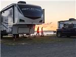 A couple passing by a parked fifth wheel at SUN OUTDOORS CHINCOTEAGUE BAY - thumbnail