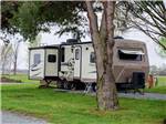 A travel trailer parked in a gravel site at MYSTIC WATERS FAMILY CAMPGROUND - thumbnail