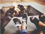 Three people's feet by the fire pit at JETSTREAM RV RESORT AT WHARTON - thumbnail