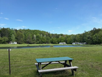 Picnic table at site with water view at Wake in the Woods Aquapark & Campground - thumbnail