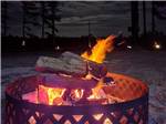 A lit up fire pit at night at DREAM RV PARKS - thumbnail