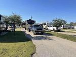 Open grass area next parked trailers Plantation Place RV Park - thumbnail