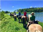 Family horseback riding alongside a river - thumbnail