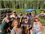 A group of friends smiling for the camera after ATVing in a meadow - thumbnail