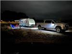 A truck and travel trailer in a RV site lit up at night at at THE STATION RV RESORT - thumbnail