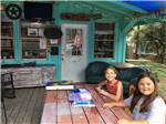 Two girls doing crafts by the office at REBECCA CREEK CAMPGROUNDS - thumbnail