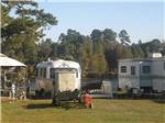 An Airstream and trailer parked next to the water at BELLS MARINA RV RESORT - thumbnail