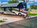 A couple sitting in front of their motorhome at CANOPY LUXURY RV RESORT - thumbnail