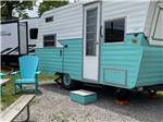 A vintage trailer next to two chairs at DANCING FIRE GLAMPING AND RV RESORT - thumbnail