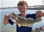 A boy holding up a fish he caught at LUCKY LAKE 208 - thumbnail