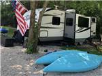 A travel trailer with blue kayaks next to it at SUNDOWNER RV PARK - thumbnail
