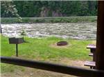 A bench and fire pit near the river at THREE RIVERS RESORT - thumbnail