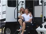 A couple sitting at the doorsteps of their RV at LAKE DEWBERRY RV RESORT - thumbnail