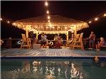 A tiki hut by the swimming pool lit up at night at THE PALAPA RV BEACH RESORT - thumbnail