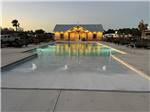 The outdoor pool lit up at dusk at SUN CITY RV PARK - thumbnail