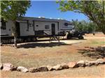 A fifth wheel trailer parked in a dirt site at SHEPHERD FAMILY CABINS & RV CAMPGROUND - thumbnail