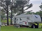 A fifth wheel trailer parked under a tree at HEAVENLY WATERS RV PARK - thumbnail