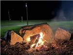 A nighttime campfire near large rocks - thumbnail