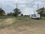 Trailer and table in grass site at Windmill Ranch RV Park & Cabins - thumbnail