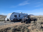 Trailer and ATV in gravel site at Atomic City RV Park - thumbnail