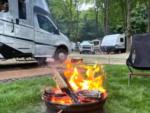 Parked RV near fire pit at site Forest Haven Campground - thumbnail