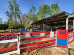 Outside view of petting farm with red fence at HITCHINPOST RV PARK AND CAMPGROUND - thumbnail