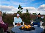 Couples sitting around a fire pit at TROPIC HIDEAWAY RV RESORT - thumbnail