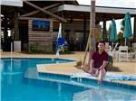 A man with his feet in the pool at TROPIC HIDEAWAY RV RESORT - thumbnail