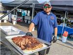 A man standing next to some bbq food at WORLD WIDE TECHNOLOGY RECEWAY CAMPGROUND - thumbnail