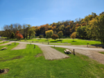 Tree lined RV sites with picnic tables at Pecatonica River Trails Park - thumbnail