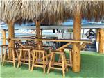A tiki bar under a shaded thatched roof - thumbnail