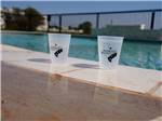 Two drinks on the edge of the pool at Crossroads Luxury RV Park - thumbnail