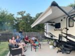 A family sitting next to their trailer at TIMBER RIDGE RV PARK - thumbnail