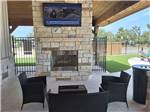 Covered outdoor fireplace with seating and TV - thumbnail