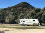 Fifth-wheel trailer with green hill in the background at LOST MAPLES RV AND CAMPING - thumbnail