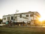 Family sits at a picnic table in front of a 5th wheel at SANDUSKY RV RESORT - thumbnail