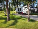 A fifth-wheel with a slide-out at site at WOODLAND CREEK RV PARK - thumbnail