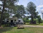 Travel Trailer on a gravel site with picnic table and fire pit at Leaning Pines Campground and Cabins - thumbnail