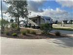 RV parked with car on lot with cloudy sky - thumbnail