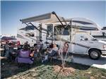 RV parked with a group of people sitting outside in a circle - thumbnail