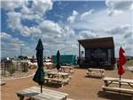 Picnic benches with umbrellas in front of a stage - thumbnail