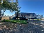 An RV in a grassy shaded RV site at Waterfront Hideaway Ranch - thumbnail