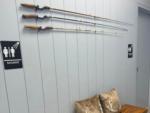 A bench under three fishing poles mounted to the wall - thumbnail