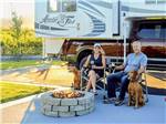 Two people with two dogs sitting by an RV - thumbnail
