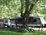 Trailer by a tree at Red Barn Campground & Restaurant - thumbnail