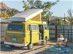 Man lounging outside of a camper bus - thumbnail